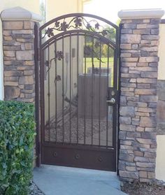 a gated entrance to a home with stone pillars