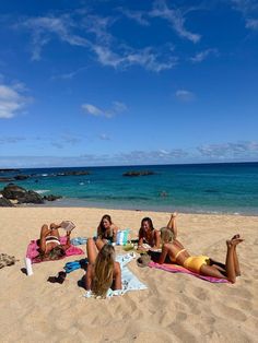 four women are laying on the beach in their bathing suits