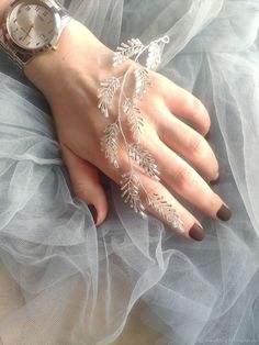 a woman's hand with white lace on it and a watch in the background