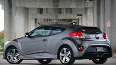 a silver sports car parked in front of an overpass