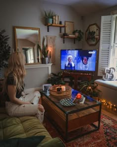 a woman sitting on a couch watching tv