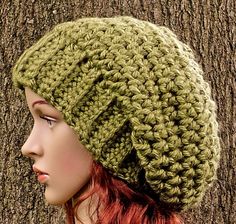 a woman wearing a green crocheted beanie hat next to a brown tree