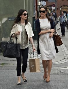 two women are walking down the street with shopping bags in hand and one is carrying a purse