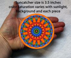 a hand holding an orange and blue circular object with text describing how to use the suncather size 3 5 inches color saturation varies with sunlight, background and each piece