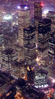 an aerial view of the city at night with skyscrapers lit up in red and blue