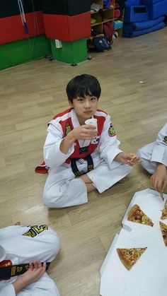 two boys sitting on the floor eating pizza