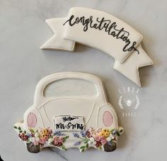 a cake shaped like a car with flowers on the front and side, next to a sign that says congratulations