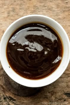 a white bowl filled with brown liquid on top of a wooden table