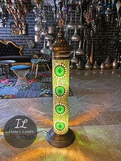 a green lamp sitting on top of a table next to a wall filled with hanging lights