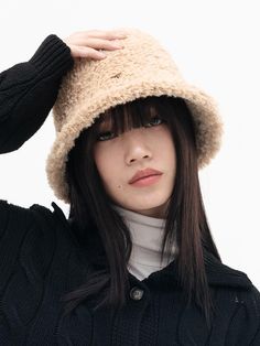 a young woman wearing a black sweater and a beige hat is posing for the camera