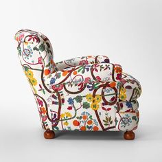 an upholstered chair with colorful flowers and vines on the back, sitting against a white background