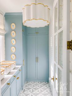 a blue and white bathroom with gold trim on the doors, cabinets, and chandelier