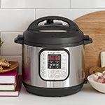 an electric pressure cooker sitting on top of a counter next to books and other items