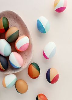 colorful painted eggs in a bowl on a white surface