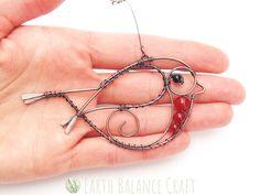 a hand holding a wire sculpture that looks like a fish on it's back