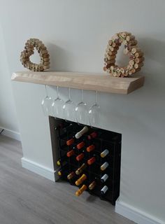 two wine glasses sitting on top of a mantle next to bottles of wine and corks