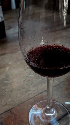 a glass of wine sitting on top of a wooden table