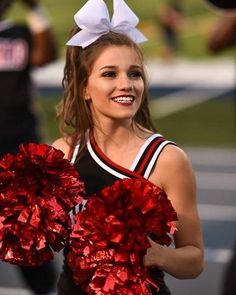 a cheerleader is smiling and holding her pom poms