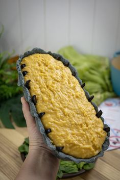 a person holding up a cake with yellow frosting