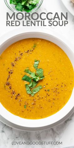 a white bowl filled with red lentil soup and topped with cilantro leaves