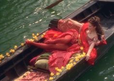 a woman in a red dress is floating on a boat