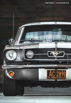 the front end of an old mustang car with a white stripe on it's hood