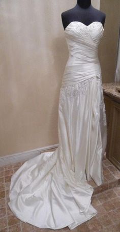 a white wedding dress on display in a room with tile flooring and beige walls