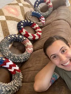 a woman laying on top of a brown couch covered in american flags braided bracelets