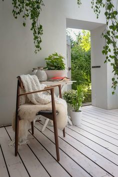 a chair sitting on top of a wooden floor next to a table with plants in it