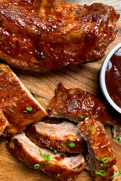 barbecue ribs with sauce and green onions on a cutting board next to a bowl of bbq sauce