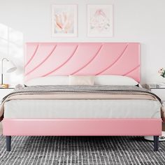 a bed with pink headboard and foot board in a white walled bedroom area next to two pictures on the wall