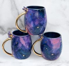 three coffee mugs sitting on top of a white marble counter next to each other