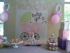 a baby shower party with pink and purple decorations, balloons and cupcakes on the table