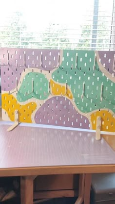 a wooden bench sitting next to a window covered in polka dot paper on top of a table