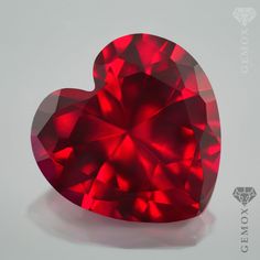 a red heart shaped diamond sitting on top of a table