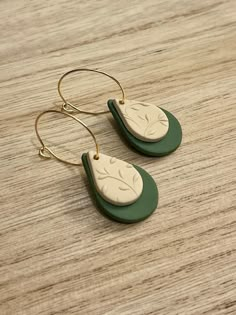 a pair of green and white earrings sitting on top of a wooden table next to each other