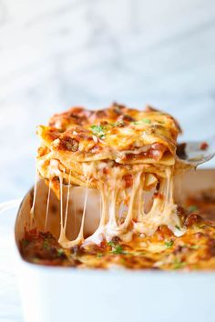 a spoon full of lasagna casserole being lifted from a white dish