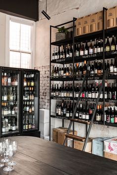 the shelves are filled with wine bottles and empty glasses on the table in front of them