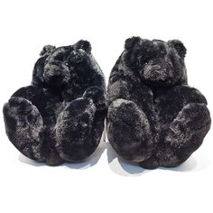 two black teddy bears sitting next to each other on a white surface with one stuffed animal in the middle