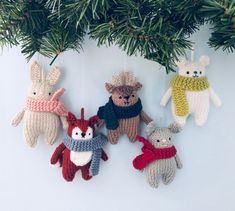 crocheted christmas ornaments hanging from a tree branch with pine branches in the background