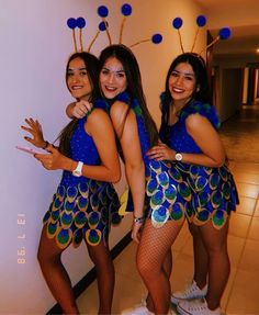 three girls dressed in peacock costumes posing for the camera