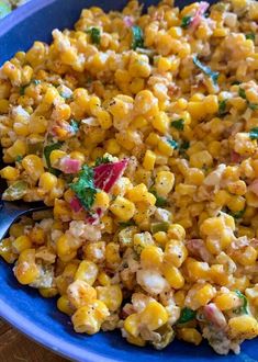 a blue bowl filled with corn and garnished with parsley on the side