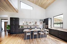 a large kitchen with wooden floors and white walls, along with black cabinets and counter tops