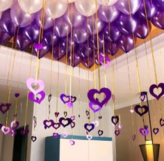 purple and white balloons hanging from the ceiling in a room with other decorations on it