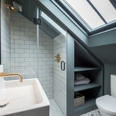 a white toilet sitting under a bathroom window next to a sink and a bath tub