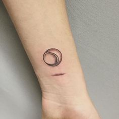 a small black circle tattoo on the wrist