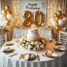 a white table topped with a cake covered in gold foil balloons and surrounded by chairs