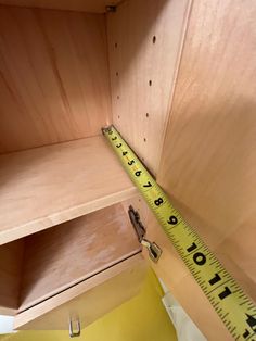 a wooden shelf with a measuring tape on the top and bottom part in front of it