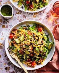 two white bowls filled with salad next to each other on top of a pink napkin