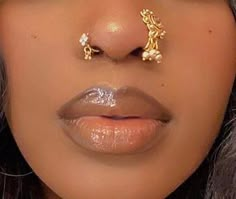 a close up shot of a woman with gold nose piercings on her nose and lips